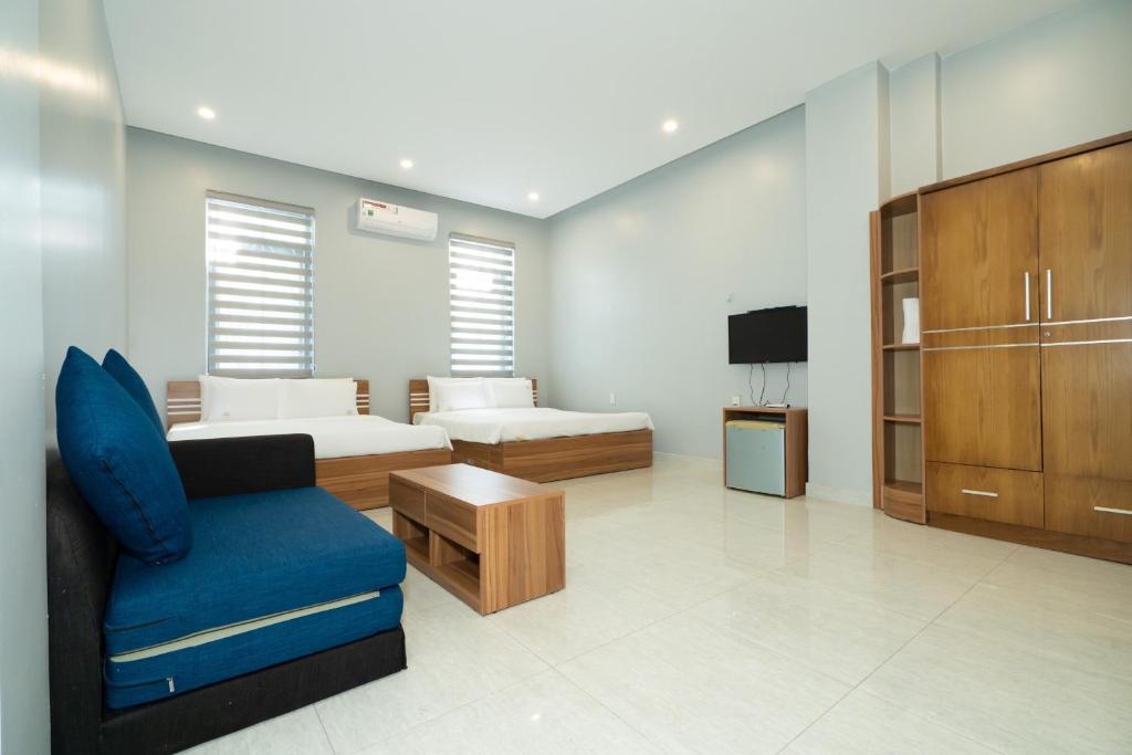 Phòng nghỉ rộng với hai giường gỗ, sofa xanh, bàn trà và tủ gỗ lớn