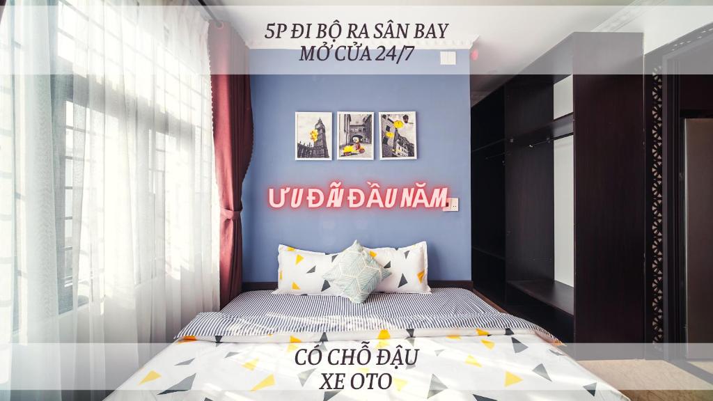 Phòng ngủ một giường đôi, ga họa tiết hình học, tường xanh và tủ gỗ tối màu dưới lớp chữ quảng cáo