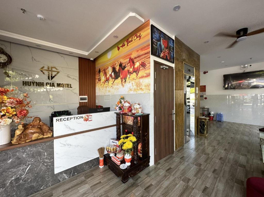 Quầy lễ tân Huynh Gia Motel với logo trên tường, tranh ngựa lớn, bàn đá trắng và bàn thờ trang trí