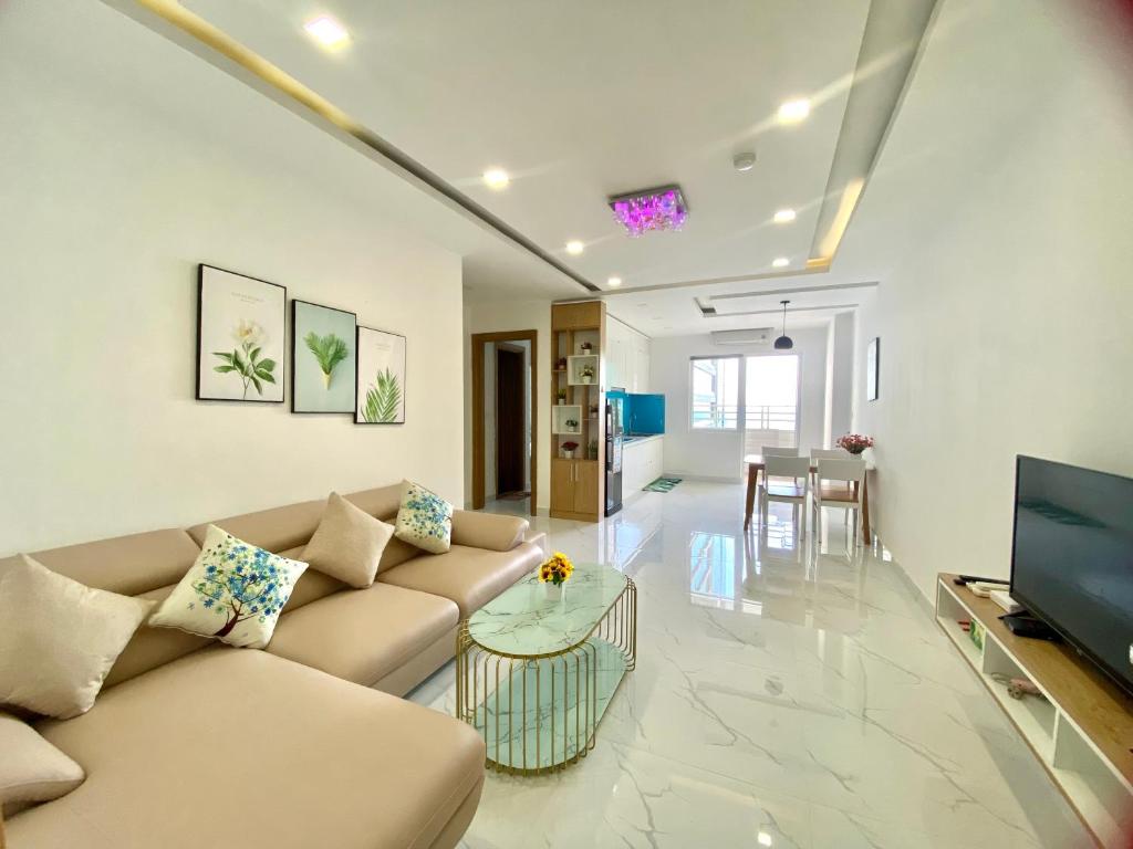 Phòng khách với sofa góc màu be, bàn đôi mặt đá và khu ăn uống cạnh cửa sổ
